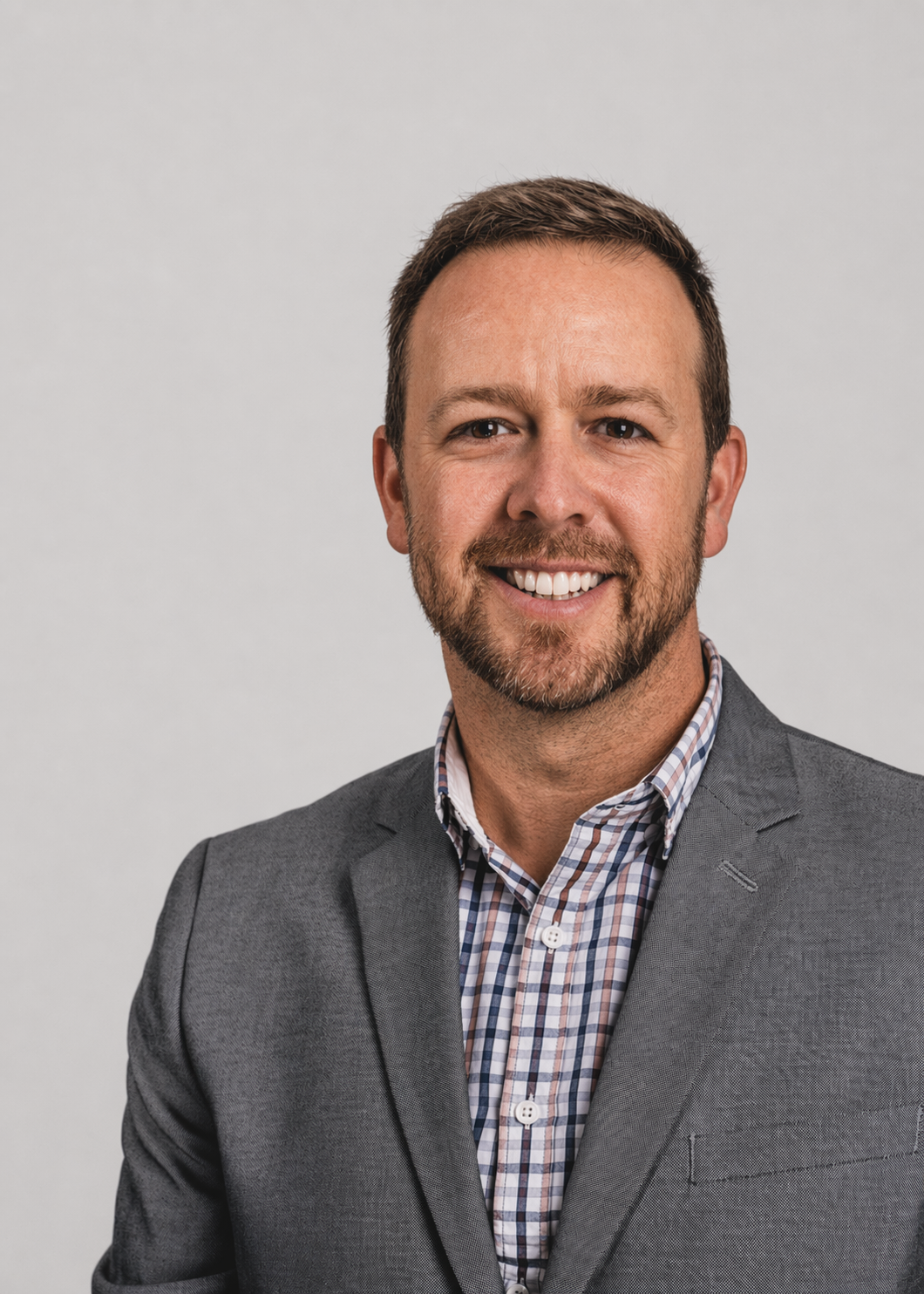 Thomas Graham smiling in a blazer and checkered shirt